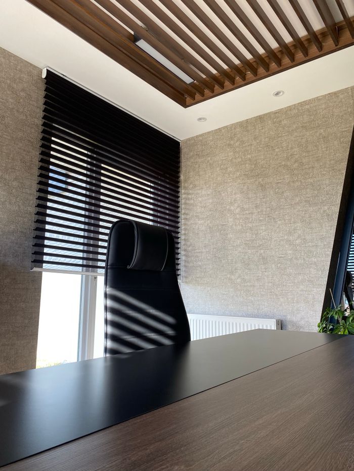 Contemporary office interior featuring a sleek desk and modern blinds for a professional workspace.