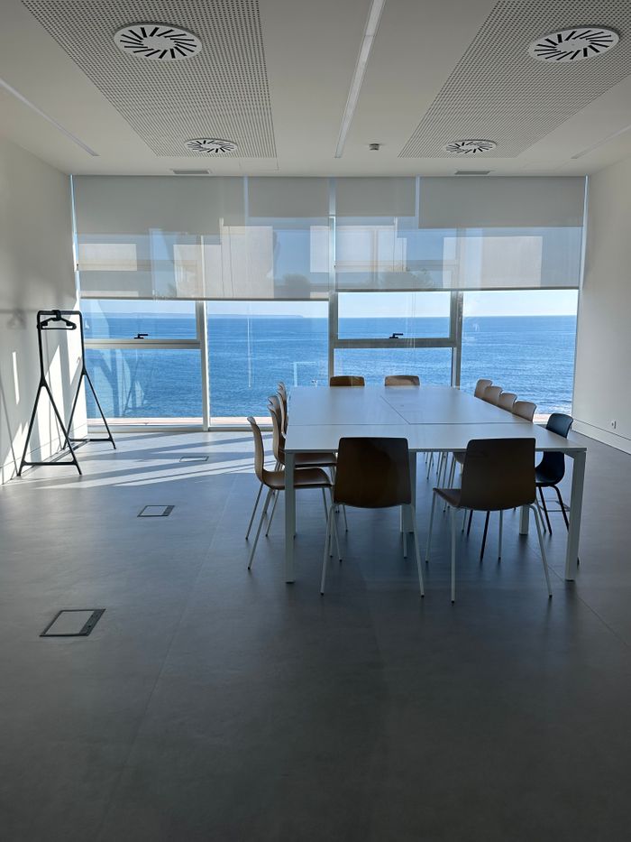 Spacious conference room with large windows overlooking the ocean, offering a bright and serene workspace.