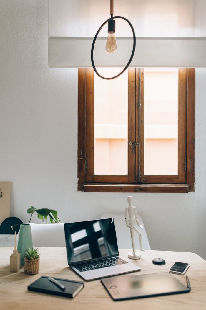 Aesthetic workspace featuring a laptop, decor, and natural light from a wooden window.